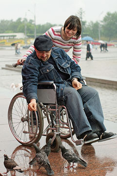a social worker assisting a wheelchair-bound senior citizen